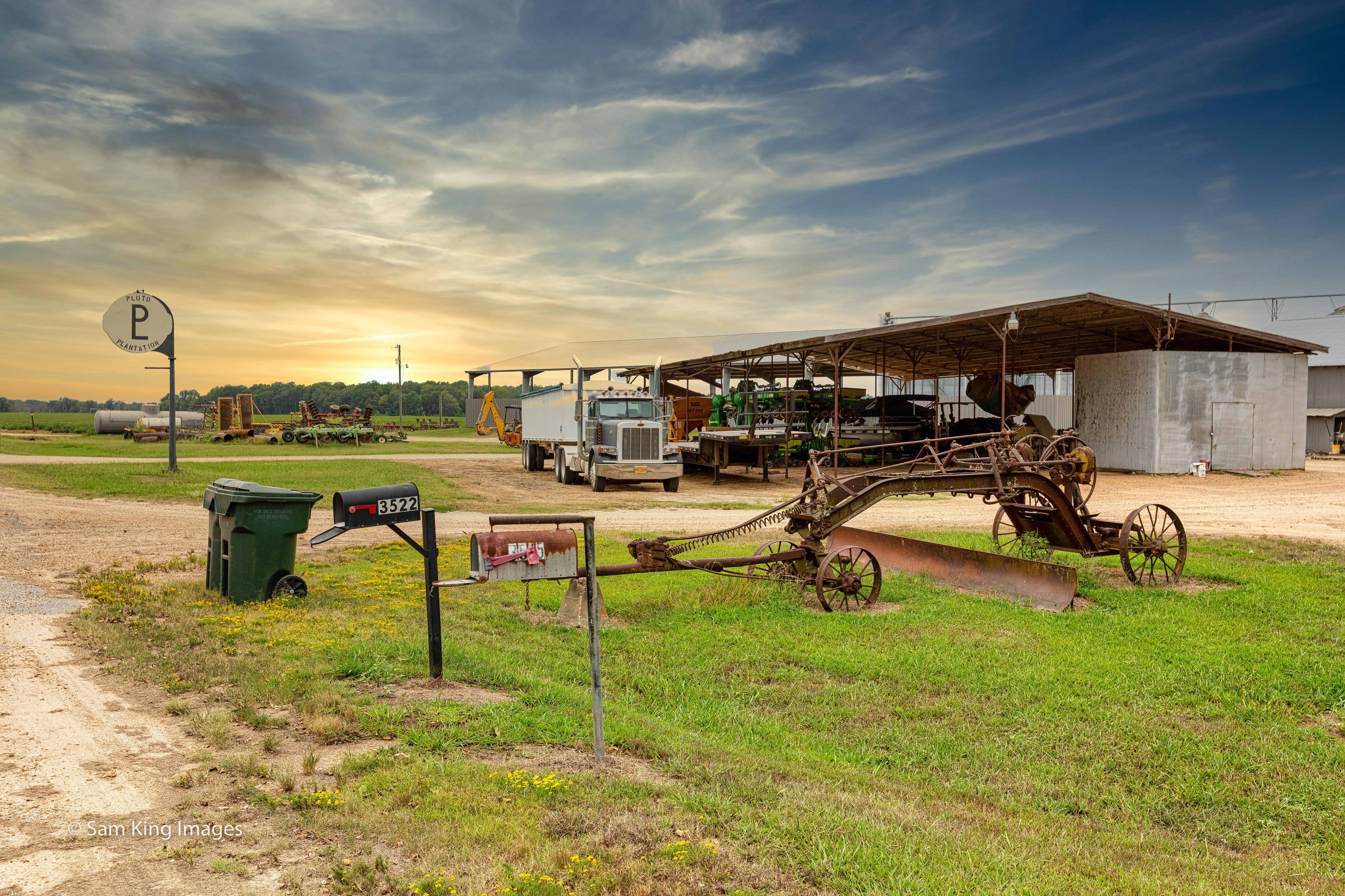 Farm equipment and an 18-wheeler are parked outside of Pluto Plantation. (Sam King)