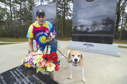 Alan Goff of Hattiesburg poses by flowers at the Lynyrd Skynyrd monument in Gillsburg on Wednesday.