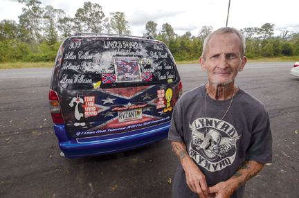 Terry Thomas of Mobile, Ala., poses by his van adorned with Lynyrd Skynyrd imagery near the monument.