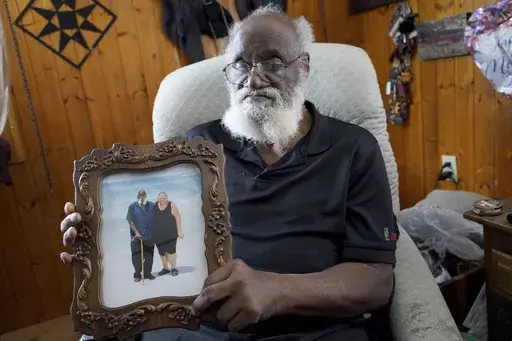 Kenny Pollard, 75, holds a photo in his home from a vacation that he and his wife, Elizabeth, took to Clearwater Beach, Fla., approximately 10 years ago. (AP Photo/Matt Freed)