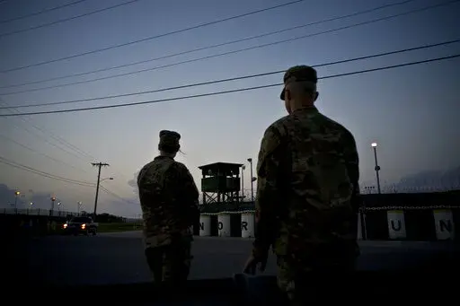 In this June 5, 2018 photo, reviewed by U.S. military officials, troops stand guard outside Camp Delta at the Guantanamo Bay detention center, in Cuba. The 20th anniversary of the first prisoners' arrival at the Guantanamo Bay detention center is on Tuesday, Jan. 11, 2022. There are now 39 prisoners left. At its peak, in 2003, the detention center held nearly 680 prisoners. (AP Photo/Ramon Espinosa, File)