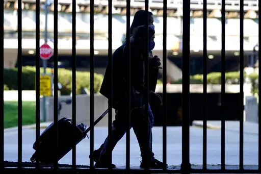 Travelers wear mask as they walk to a parking lot at O'Hare International Airport in Chicago, Friday, July 2, 2021.  Travel in the second half of 2021 was a chaotic mess in many capacities, with canceled flights, long delays and other interruptions.  (AP Photo/Nam Y. Huh, File)
