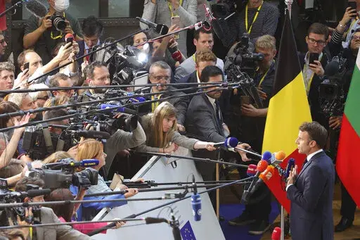 France's President Emmanuel Macron speaks with the media as he arrives for an EU summit at the EU Council building in Brussels, Thursday, Oct. 20, 2022. European Union leaders were heading into a two-day summit Thursday with opposing views on whether, and how, the bloc could impose a gas price cap to contain the energy crisis fueled by Russian President Vladimir Putin's invasion of Ukraine and his strategy to choke off gas supplies to the bloc at will. (AP Photo/Olivier Matthys)