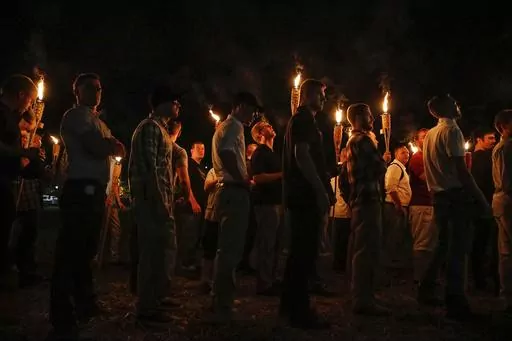 Multiple white nationalist groups march with torches through the University of Virginia campus on Aug. 11, 2017, in Charlottesville, Va. Nearly six years after a large gathering of white nationalists in Charlottesville erupted in violent clashes with counter protesters, a grand jury in Virginia has indicted multiple people on felony charges for carrying flaming torches with the intent to intimidate. (Mykal McEldowney/The Indianapolis Star via AP, File)