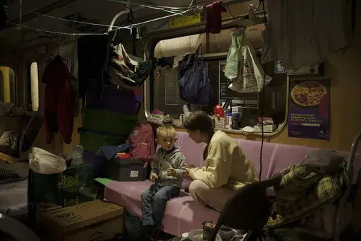 People sit inside a subway car, parked in a station being used as a bomb shelter, as Russian attacks continue in Kharkiv, Ukraine, Friday, March 25, 2022. (AP Photo/Felipe Dana)