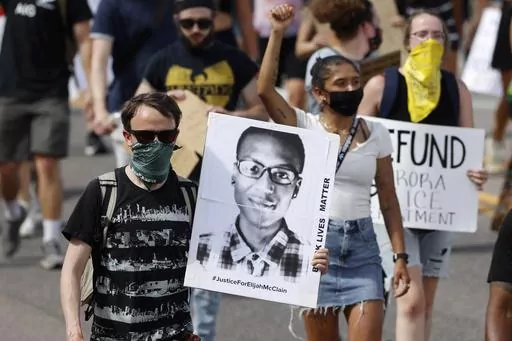 A demonstrator carries an image of Elijah McClain during a rally and march in Aurora, Colo., June 27, 2020. McClain, a 23-year-old Black man, died after a 2019 encounter with police. (AP Photo/David Zalubowski, File)