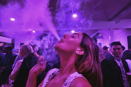 A guest takes a puff from a marijuana cigarette at the Sensi Magazine party celebrating the 420 holiday in the Bel Air section of Los Angeles, April 20, 2019. Marijuana advocates are gearing up for Saturday, April 20, 2024. Known as 4/20, marijuana's high holiday is marked by large crowds gathering in parks, at festivals and on college campuses to smoke together. This year, activists can reflect on how far the movement has come. (AP Photo/Richard Vogel, File)