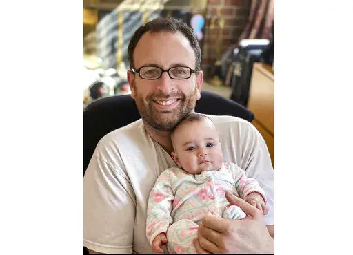 In this Oct. 2020 photo released by Eugene Brusilovskiy, Eugene holds his then-3-month-old daughter, Aya, in Philadelphia. Since Aya was born in the early months of the pandemic, Brusilovskiy was able to stay at home and spend time with her. A survey from the U.S. Census Bureau says parents shared more time with their children from March to June 2020, when coronavirus-lockdowns were at their most intense in many part of the U.S., than they had in previous years. (Eugene Brusilovskiy via AP)