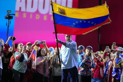 President Nicolas Maduro waves a Venezuelan flag during his closing election campaign rally in Caracas, Venezuela, Thursday, July 25, 2024. Maduro is seeking re-election for a third term in the July 28 vote. (AP Photo/Fernando Vergara)