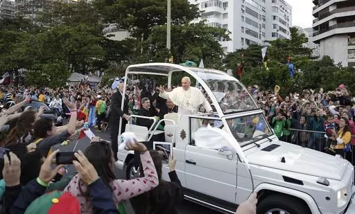Pope Francis waves to people from his popemobile along the Copacabana beachfront as he arrives for the Stations of the Cross procession in Rio de Janeiro, Brazil, Friday, July 26, 2013. When Pope Francis made the first foreign trip of his papacy, to Rio de Janeiro for World Youth Day in 2013, he urged young people to make a "mess" in their local churches, to shake things up even if it ruffled the feathers of their bishops. (AP Photo/Andre Penner, File)