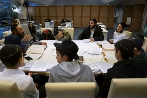 Young refugees from Israel listen to a rabbi in a Yashiva in a Jewish refugee camp in Balatonoszod, Hungary, Tuesday Nov. 7, 2023. The camp, which houses around 250 people, including 100 children, provides shelter for Jewish refugees, some of whom escaped war both in Ukraine and Israel. (AP Photo/Bela Szandelszky)