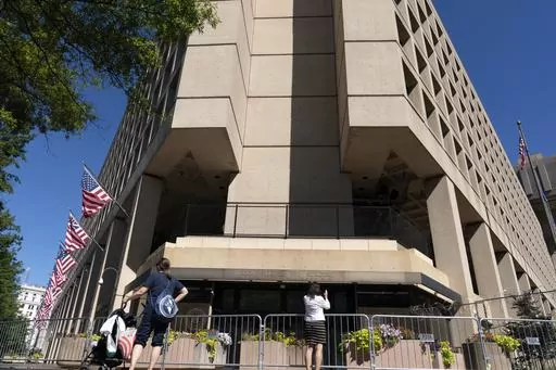 People take photos of the FBI building headquarters in Washington, Aug. 13, 2022. A federal judge in Washington is weighing whether to hold in contempt Catherine Herridge, a veteran journalist who has refused to identify her sources for stories about a Chinese scientist who was investigated by the FBI but never charged. (AP Photo/Jose Luis Magana, File)