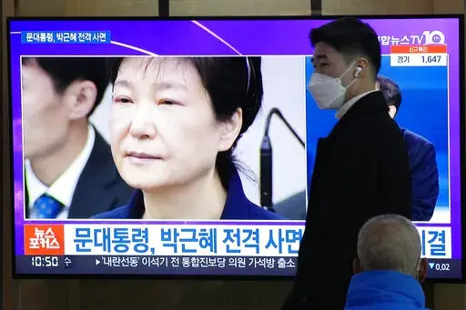 A man passes by a TV screen showing a file image of former South Korean President Park Geun-hye during a news program at the Seoul Railway Station in Seoul, South Korea, Friday, Dec. 24, 2021. The South Korean government said Friday it will grant a special pardon to Park, who is serving a lengthy prison term for bribery and other crimes. The Korean letters read "President Moon Jae-in pardons Park Geun-hye." (AP Photo/Ahn Young-joon)