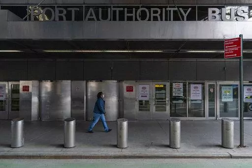 A pedestrian passes the 9th Avenue shuttered doors of the Port Authority Bus Terminal, Friday, Jan. 22, 2021, in New York. The police agency that patrols New York City’s main bus terminal has agreed to stop sending plainclothes officers into its public bathrooms to try and catch people propositioning strangers for sex, a type of sting long criticized by activists as a discriminatory relic of an era of crackdowns predominantly aimed at gay men. (AP Photo/Mary Altaffer, File)