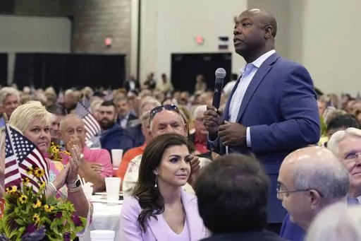 Republican presidential candidate Sen. Tim Scott, R-S.C., right, walks by Casey DeSantis, wife of GOP rival and Florida Gov. Ron DeSantis, center, as he speaks at Rep. Jeff Duncan's Faith & Freedom BBQ fundraiser, Aug. 28, 2023, in Anderson, S.C. Republicans are responding to a late summer spike in COVID-19 by raising familiar fears that government-issued lockdowns and mask mandates are on the horizon. GOP presidential hopefuls including Florida Gov. Ron DeSantis, South Carolina Sen. Tim Scott a