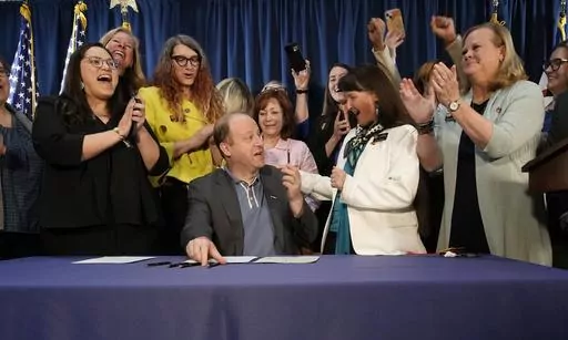 Colorado Gov. Jared Polis, front center, is applauded by, state Sen. Julie Gonzales, far left, state Rep. Brianna Titone, second from left, Lt. Gov. Dianne Primavera, third from left, state Sen. Sonya Jaquez Lewis and state Rep. Meg Froelich after he signed the first of three bills that enshrined protections for abortion and gender-affirming care procedures and medications during a ceremony with bill sponsors and supporters, Friday, April 14, 2023, in the State Capitol in Denver. (AP Photo/David