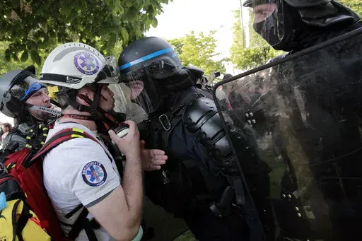 Riot policemen confront a first aid voluntee rafter clashes during a May Day demonstration march from Republique, Bastille to Nation, in Paris, France, Sunday, May 1, 2022. Citizens and trade unions in France take to the streets to put out protest messages to their governments as a rallying cry against newly reelected President Emmanuel Macron. (AP Photo/Lewis Joly)