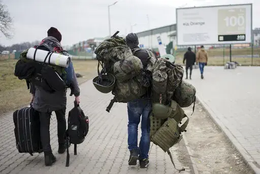 A man carries combat gear as he leaves Poland to fight in Ukraine, at the border crossing in Medyka, Poland, Wednesday, March 2, 2022. (AP Photo/Markus Schreiber, File)
