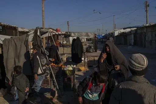 People stroll through the marketplace in the al-Hol detention camp in northeastern Syria's Hassakeh province, where tens of thousands of mostly women and children linked to the Islamic State group have been living for years, Thursday, Jan. 30, 2025. (AP Photo/Bernat Armangue)