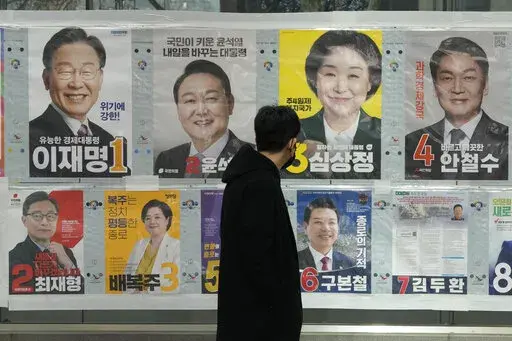 A man watches posters of presidential candidates on a street in Seoul, South Korea, March 3, 2022. Tens of millions of South Koreans are expected to vote Wednesday, March 9 to choose their new president. The winner will take office on May 10 for a single five-year term. Whoever wins, a new leader will be tasked with resolving various economic woes, easing threats from nuclear-armed North Korea and healing a nation sharply split along the lines of ideology, generation and gender. (AP Photo/Ahn Yo