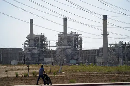 A man pushes a stroller near the AES power plant in Redondo Beach, Calif., Wednesday, Sept. 7, 2022. A record heat wave put California in a fossil fuel conundrum: The state has had to rely more heavily on natural gas to produce electricity and avoid power outages while Gov. Gavin Newsom's administration moves toward ending the use of oil and gas. (AP Photo/Jae C. Hong)