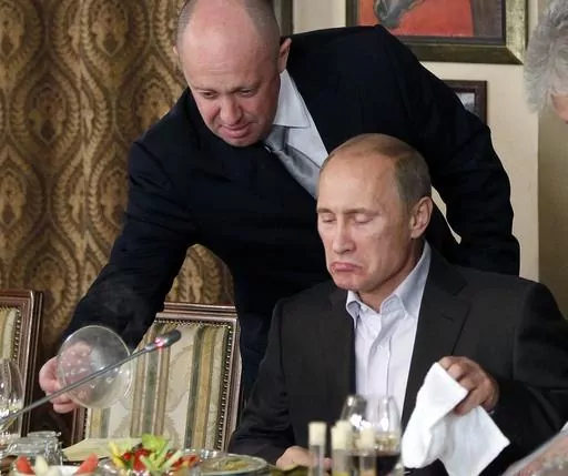 Yevgeny Prigozhin, top, serves food to Russian Prime Minister Vladimir Putin at Prigozhin's restaurant outside Moscow, Russia, on Nov. 11, 2011. When Prigozhin launched his armed rebellion that challenged the Kremlin, Western officials predicted Putin would seek vengeance against the mercenary leader. Although authorities have not yet confirmed the death of Prigozhin and his top lieutenants in Wednesday's plane crash northwest of Moscow, it sent an immediate chill through Russian official circle