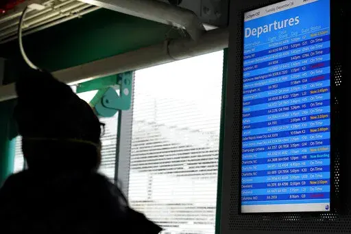 FILE - A traveler checks an information screen for flight status at O'Hare International Airport in Chicago, Ill., Tuesday, Dec. 28, 2021. Hundreds of flights were cancelled Wednesday as the omicron variant continues to create havoc both for travelers and for airlines who are having to cobble together flight crews as infections rise among pilots, flight attendants.   (AP Photo/Nam Y. Huh, File)