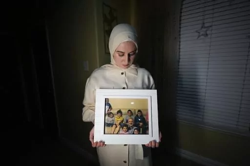Maryam Kamalmaz hold a photo of her father with some of his 14 grandchildren in Grand Prairie, Texas, Jan. 17, 2024. By any standard, the past 18 months have been remarkable for getting wrongfully detained Americans home. But not so for Kamalmaz, who has had no trace of her father, Majd Kamalmaz, since the psychologist from Texas was stopped at a checkpoint in Syria in 2017 after traveling there to visit an elderly family member. He remains one of several Americans missing in Syria, including jo