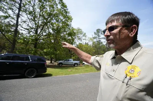 Leake County Sheriff Randy Atkinson points to a burned house where an escaped inmate exchanged gunfire with law enforcement officers Wednesday, April 26, 2023, in Conway, Miss. (AP Photo/Rogelio V. Solis, File)
