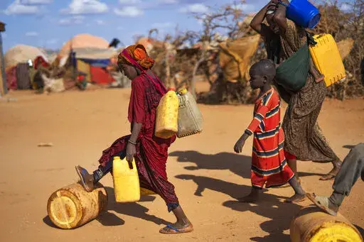 A Somali woman and children carry water at a camp for displaced people on the outskirts of Dollow, Somalia on Tuesday, Sept. 20, 2022. Madeleine Diouf Sarr, the chair of an influential negotiating bloc in the upcoming United Nations climate summit in Egypt has called for compensation for poorer countries suffering from climate change to be high up on the agenda. Sarr added that the bloc will push for funds to help developing countries adapt to droughts, floods and other climate-related events as