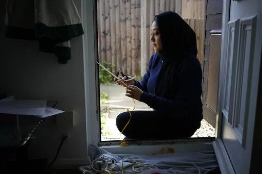 Bilqis Alam, an energy advisor from the South East London Community Energy co-operative (Selce), installs draught proofing rubber strips to the front door frame of the home of her client Tia Rutherford, in south east London, Tuesday, March 22, 2022. People across the United Kingdom will face tough choices in coming months as energy costs for millions of households are set to rise by 54% on Friday. It's the second big jump in energy bills since October, and a third may be ahead as rebounding dema
