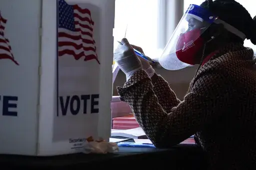 A poll worker talks to a voter before they vote on a paper ballot on Election Day in Atlanta, Nov. 3, 2020. With the November elections creeping up and Republicans imposing new restrictions on ballot access, President Joe Biden has no easy options for safeguarding voting rights despite rising pressure from frustrated activists. (AP Photo/Brynn Anderson, File)