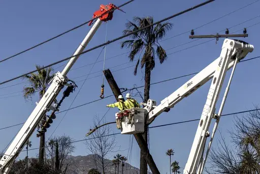 Workers with Southern California Edison remove a utility pole damaged by the Eaton Fire in Altadena, Calif., Sunday, Jan. 12, 2025. (Stephen Lam/San Francisco Chronicle via AP)