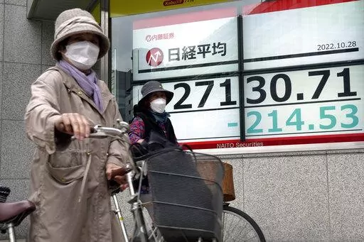 People push their bicycle in front of an electronic stock board showing Japan's Nikkei 225 index at a securities firm Friday, Oct. 28, 2022, in Tokyo. Shares were mostly lower in Asia on Friday after a mixed session on Wall Street, where tech sector losses offset gains in other parts of the market. (AP Photo/Eugene Hoshiko)