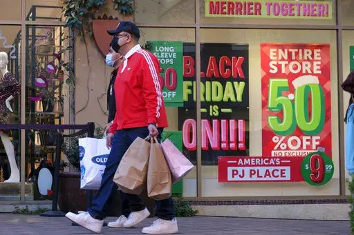 Black Friday shoppers, wearing face masks, carry bags at the Citadel Outlets in Commerce, Calif., Friday, Nov. 26, 2021. (AP Photo/Ringo H.W. Chiu)