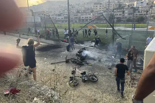 Residents rush to help injured children moments after a rocket attack hit a soccer field in the Druze town of Majdal Shams in the Israeli-controlled Golan Heights, Saturday, July 27, 2024. (AP Photo/Hassan Shams)
