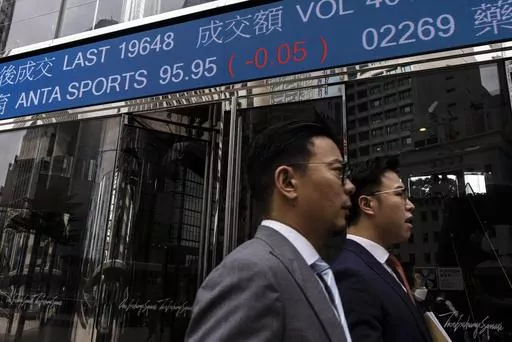 Pedestrians pass by the Hong Kong Stock Exchange electronic screen in Hong Kong, Wednesday, April 26, 2023. Asian shares are trading mostly lower, as worries about the health of global economies grew after a tumble on Wall Street despite some better-than-expected earnings reports. (AP Photo/Louise Delmotte)