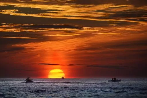 The sun rises over fishing boats in the Atlantic Ocean, Sept. 8, 2022, off of Kennebunkport, Maine. A system of ocean currents that carries heat northward across the North Atlantic could collapse during this century, according to a new study, and scientists have said before such a collapse could cause catastrophic sea-level rise and extreme weather across the globe. (AP Photo/Robert F. Bukaty, File)