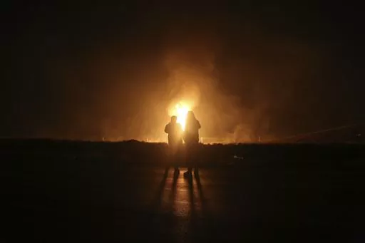 Two men look at flames after a natural gas pipeline explodes outside the city of Boroujen in the western Chaharmahal and Bakhtiari province, Iran, in early Wednesday, Feb. 14, 2024. Explosions struck a natural gas pipeline in Iran early Wednesday, with an official blaming the blasts on a "sabotage and terrorist action" in the country as tensions remain high in the Middle East amid Israel's war on Hamas in the Gaza Strip. (Reza Kamali Dehkordi/Fars News Agency via AP)