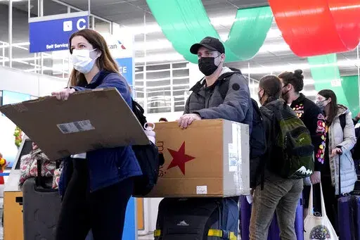 Travelers line up wearing protective masks indoors at O'Hare International Airport in Chicago, Dec. 28, 2021. U.S. District Judge Kathryn Kimball Mizelle in Tampa, Fla., on April 18, 2022, voided the national travel mask mandate as exceeding the authority of U.S. health officials. The mask mandate that covers travel on airplanes and other public transportation was recently extended by President Joe Biden's administration until May 3. (AP Photo/Nam Y. Huh, File)
