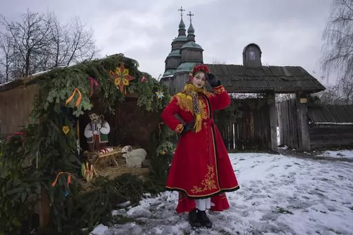 A woman dressed in national costume stands near the nativity scene to celebrate Christmas in the village of Pirogovo, outside the capital Kyiv, Ukraine, Monday, Dec. 25, 2023. (AP Photo/Efrem Lukatsky)