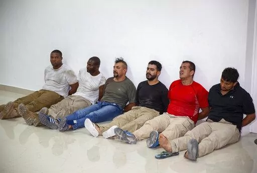 Suspects in the assassination of Haiti's President Jovenel Moise, among them Haitian-American citizens James Solages, left, and Joseph Vincent, second left, are shown to the media at the General Direction of the police in Port-au-Prince, Haiti, Thursday, July 8, 2021. U.S. officials say four key suspects in the killing of Haitian President Jovenel Moïse have been transferred to the United States for prosecution as the case stagnates in Haiti amid death threats that have spooked local judges. Th