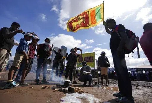 Sri Lankans boil a pot of milk as customary to welcome the dawn of Sinhalese and Tamil new year at a protest site near the president's office in Colombo, Sri Lanka, Thursday, April 14, 2022. Sri Lankans boiled pots of milk and shared milk rice and oil cakes to celebrate their traditional New Year opposite the president's office where they have camped out for a sixth day Thursday demanding the president's resignation over the country's worst economic crisis in memory. (AP Photo/Eranga Jayawardena