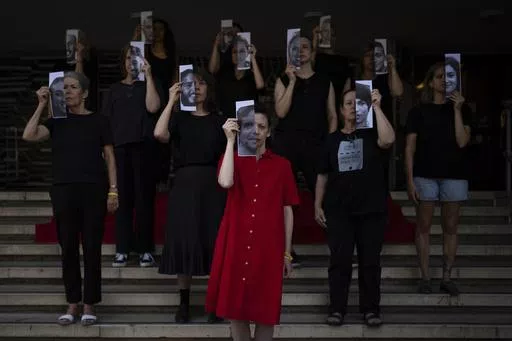 Relatives and supporters of Israeli hostages held by Hamas in Gaza hold photos of their loved ones during a performance calling for their return in Tel Aviv, Israel, Thursday, May 23, 2024. (AP Photo/Oded Balilty)