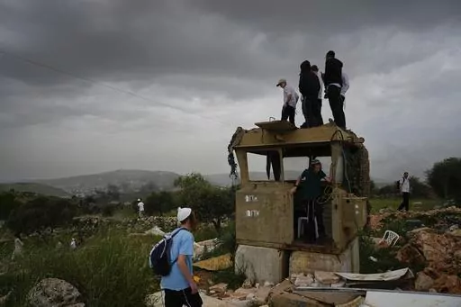 Israeli settlers stand in the outpost of Eviatar in the West Bank, Monday, April 10, 2023. Thousands led by hardline ultranationalist Jewish settlers marched to the unauthorized settlement outpost Eviatar in the northern West Bank that was cleared by the Israeli government in 2021, protected by a large contingent of Israeli soldiers and police. (AP Photo/Ariel Schalit)