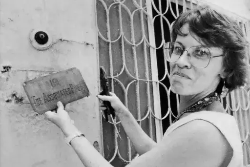 This undated photo shows Associated Press New Delhi Chief of Bureau Earleen Fisher removing the brass sign from the old bureau in New Delhi, India. (AP Photo/AP Corporate Archives, File)