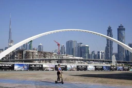 A woman rides a scooter while passing by the advertising billboards of a new residential project in Dubai, United Arab Emirates, Tuesday, Jan. 31, 2023. For the first time since a 2009 financial crisis nearly brought Dubai to its knees, several major abandoned real estate projects now show signs of life. As with its other booms, war again is driving money into Dubai and buoying its economy. This time it's Russian investors fleeing Moscow’s war on Ukraine, rather than people escaping Mideast ba