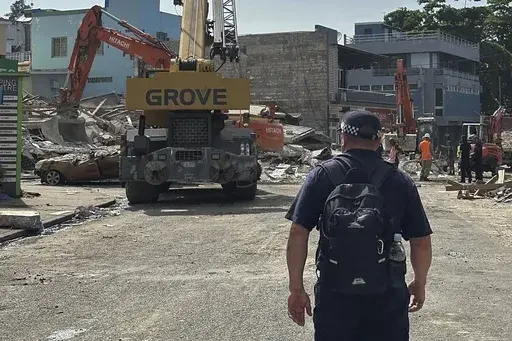 A member of Australia's Federal Police stands by a collapsed building in Port Vila, Vanuatu, Thursday, Dec. 19, 2024, following a magnitude 7.3 earthquake that struck off the coast of Vanuatu in the South Pacific Ocean, Tuesday, Dec. 17. (Australian Federal Police via AP)
