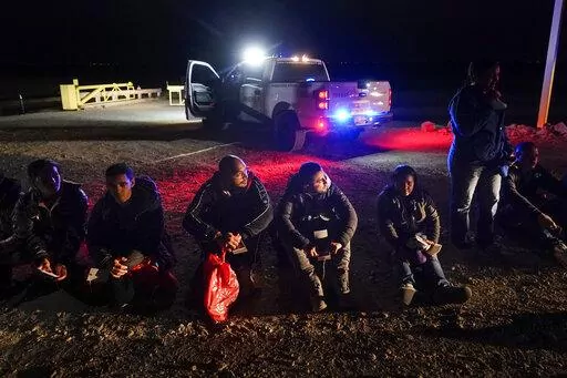 Migrants wait to be processed after crossing the border on Jan. 6, 2023, near Yuma, Ariz. The Biden administration says it will generally deny asylum to migrants who show up at the U.S. southern border without first seeking protection in a country they passed through. That mirrors an attempt by the Trump administration that never took effect because it was blocked in court. (AP Photo/Gregory Bull, File)