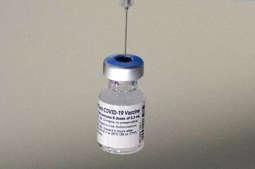 A syringe is placed into a vial of Pfizer-BioNTech vaccination at a COVID-19 clinic in Augusta, Maine, on Tuesday, Dec. 21, 2021. On Thursday, Oct. 20, 2022, Pfizer said it will charge $110 to $130 for a dose of its COVID-19 vaccine once the U.S. government stops buying the shots, but the drugmaker says it expects many people will continue receiving doses for free. (AP Photo/Robert F. Bukaty, File)